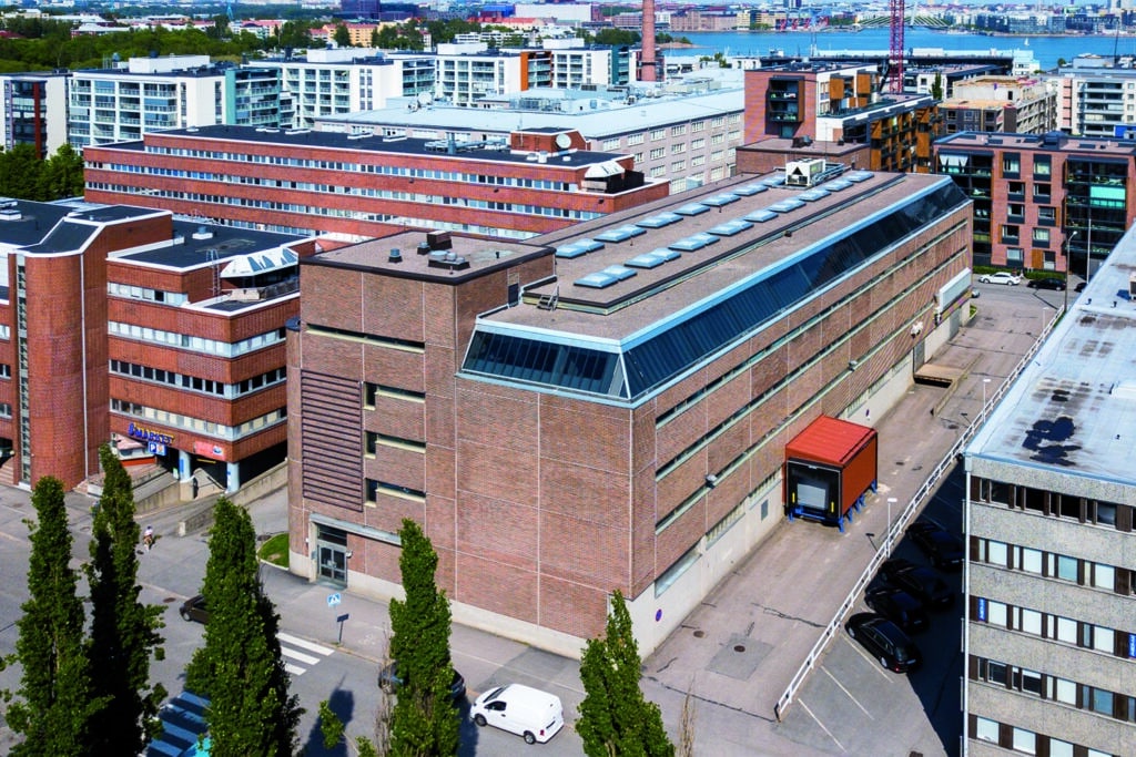Helsingin Melkonkatu 26 ilmakuvattuna Itälahdenkadulta. Punatiilisen toimitilarakennuksen seinustalla on nauhaikkunat.